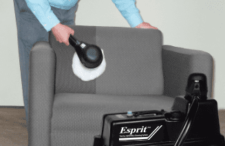 Man cleaning chair with upholstery machine.