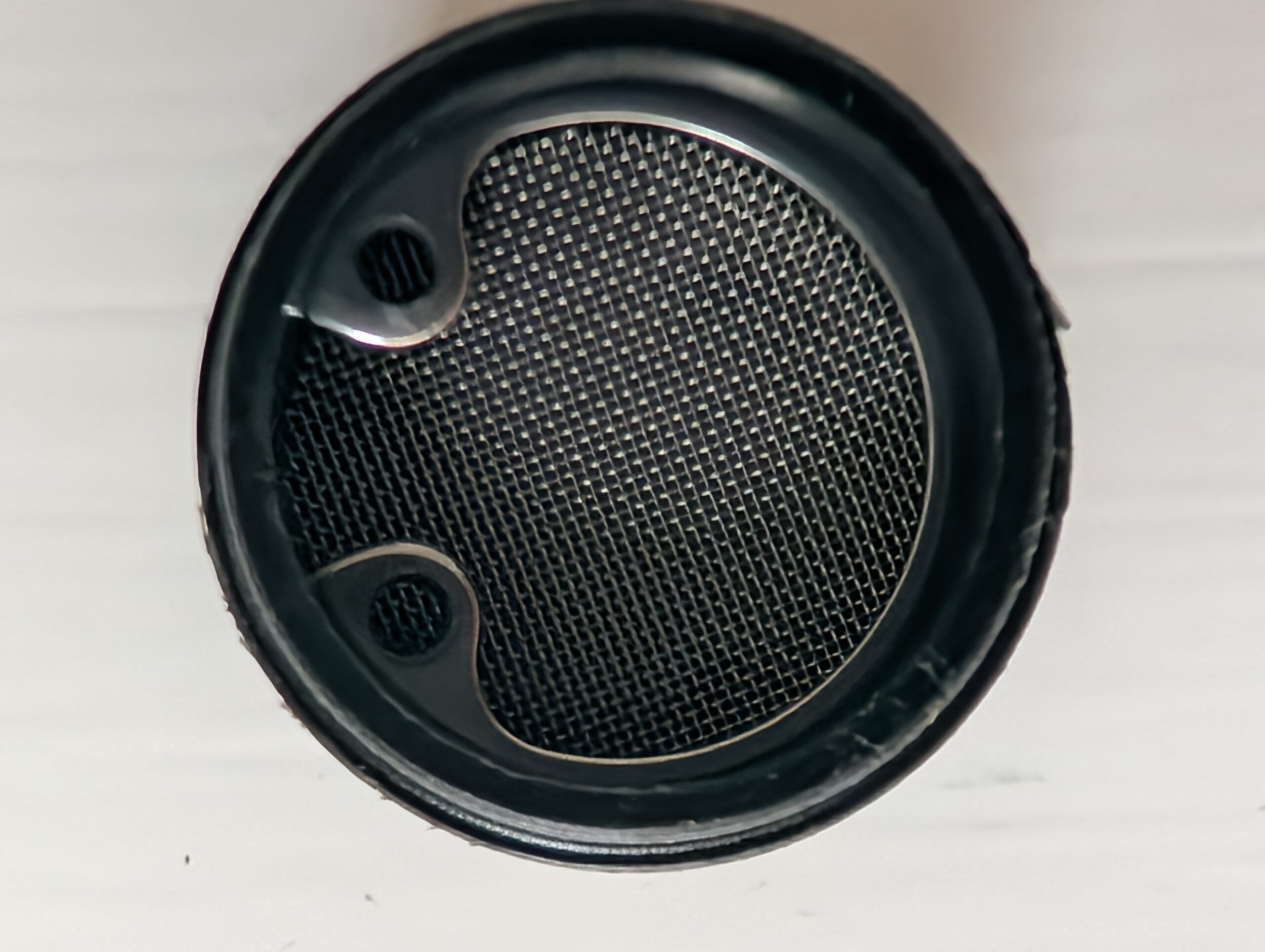 Close-up of a round black speaker grille with a mesh pattern.