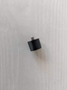 Black knob with metal screw on surface.