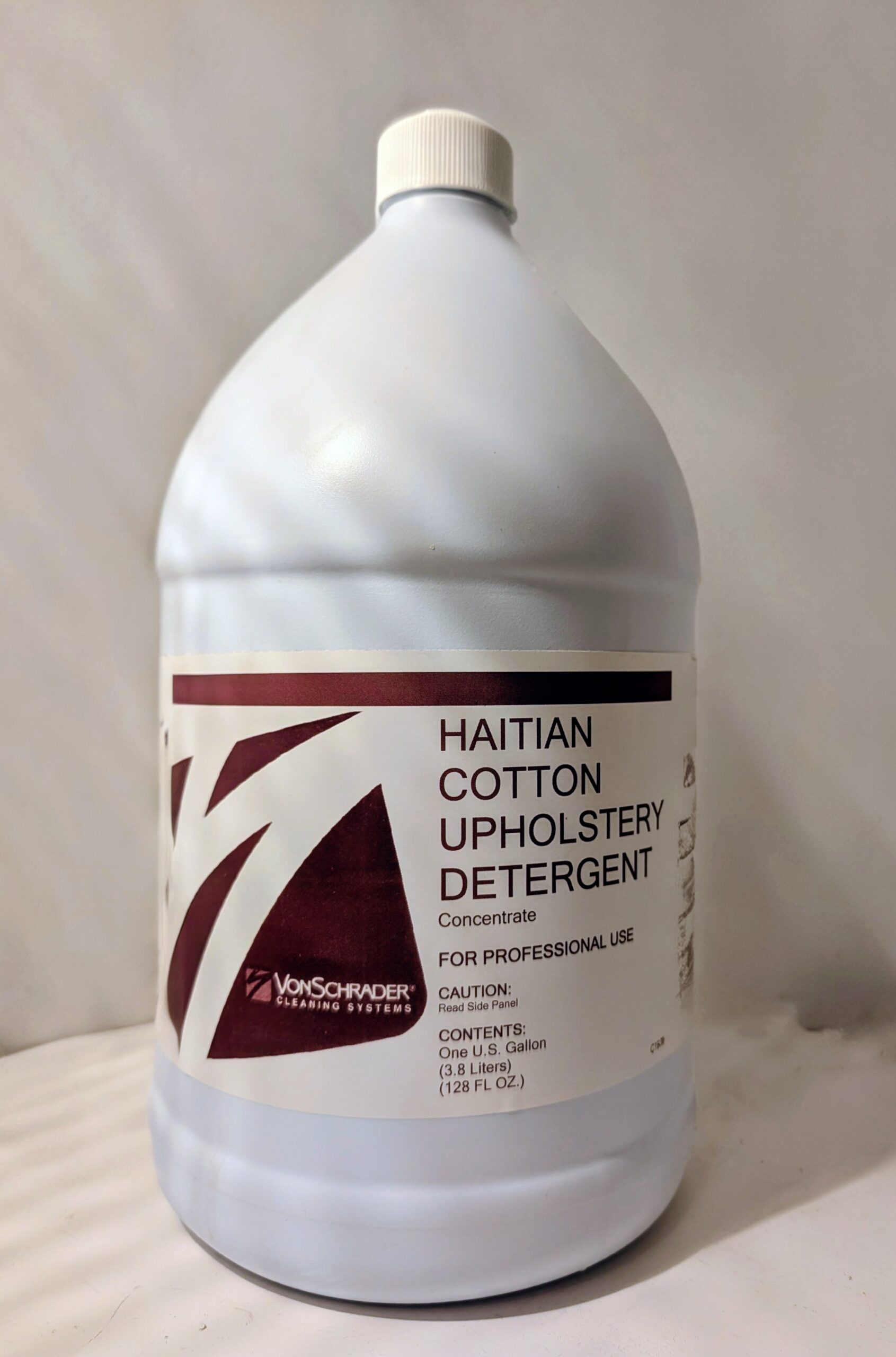 A bottle of Haitian cotton upholstery detergent with a white and maroon label.