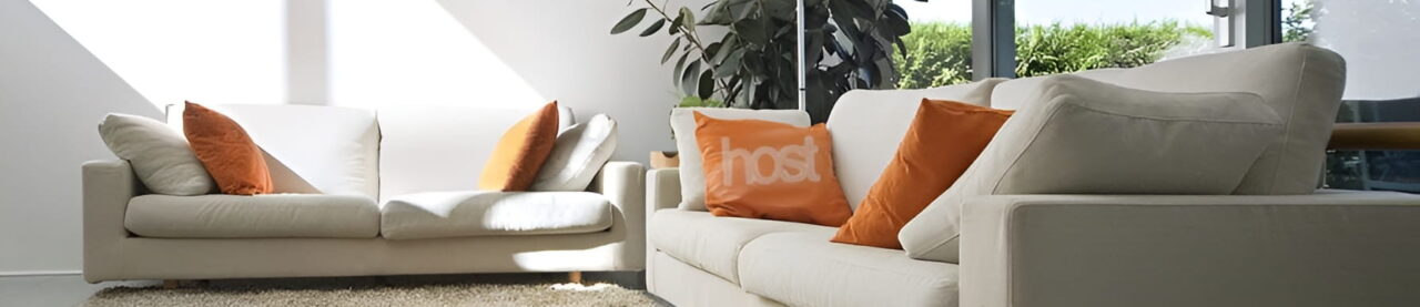 Cozy living room with white sofas and orange cushions.