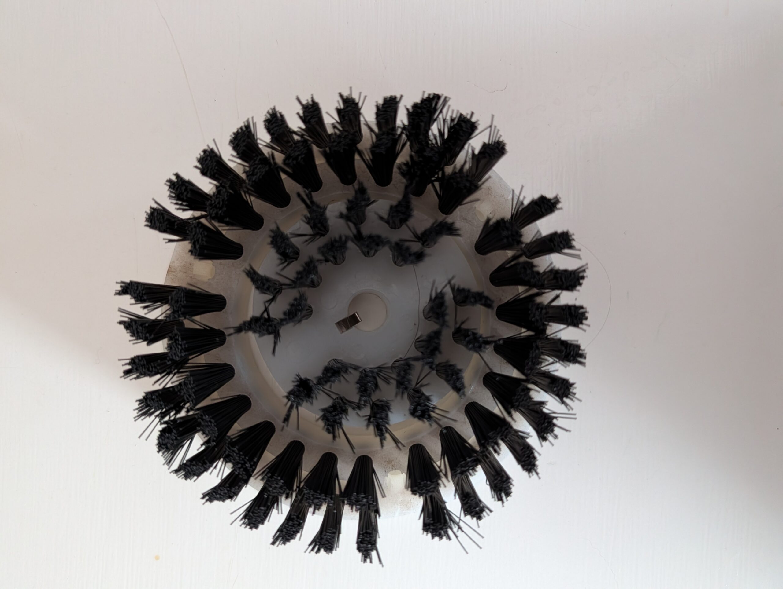 Circular arrangement of black plastic clips on a white surface.
