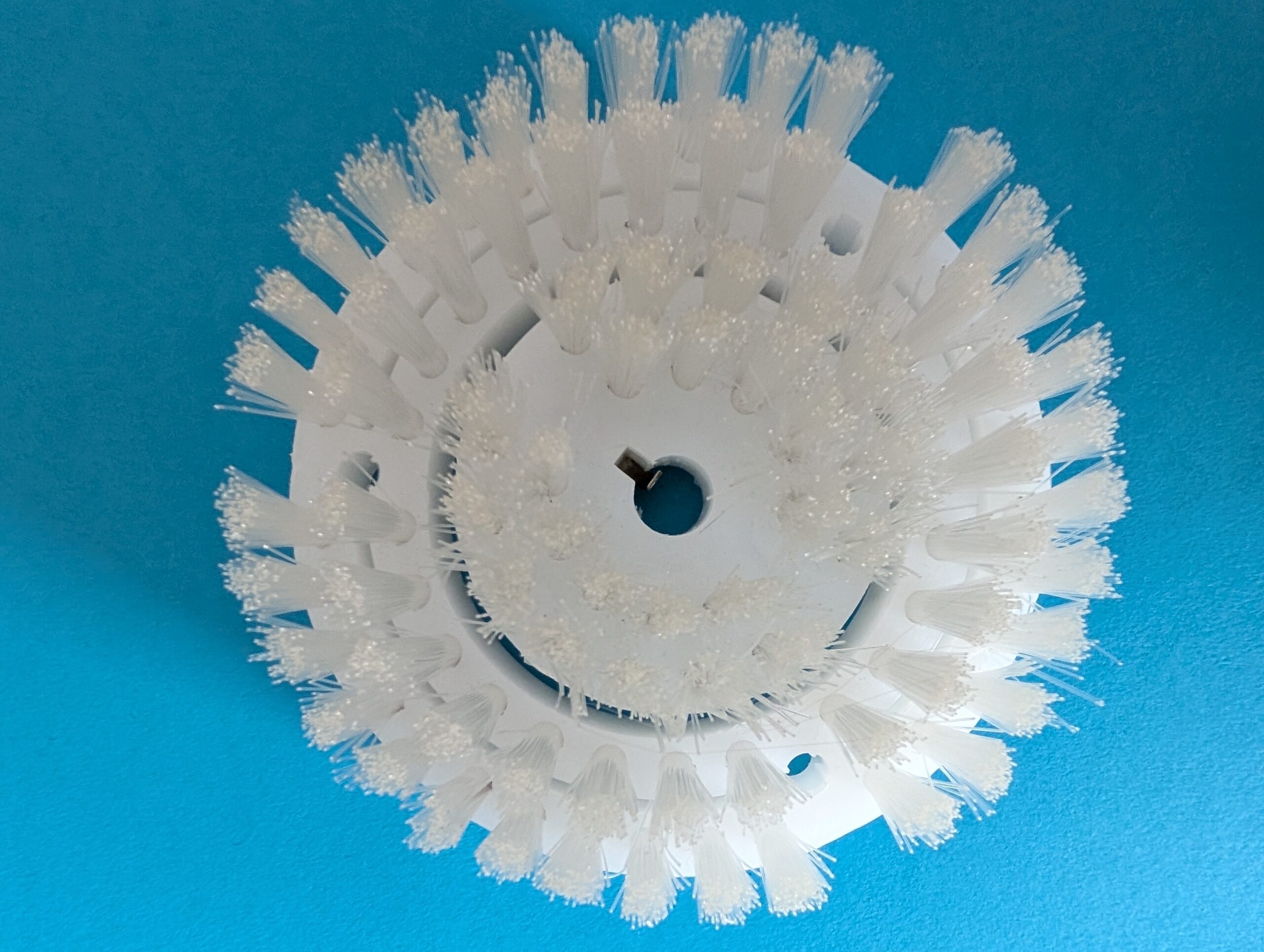 A circular plastic component with protruding rectangular tabs.