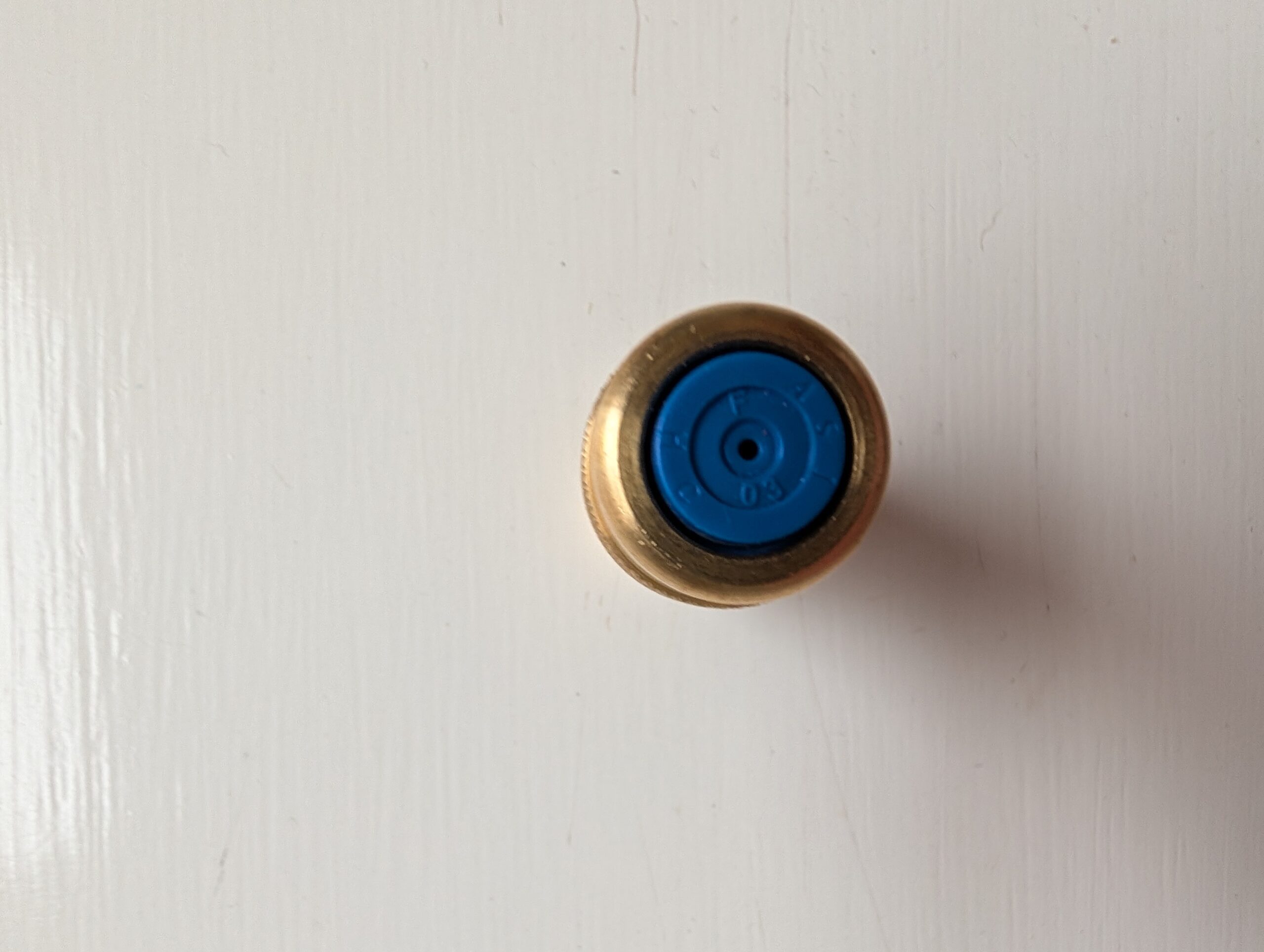 Top view of a blue and gold bottle cap against a white background.