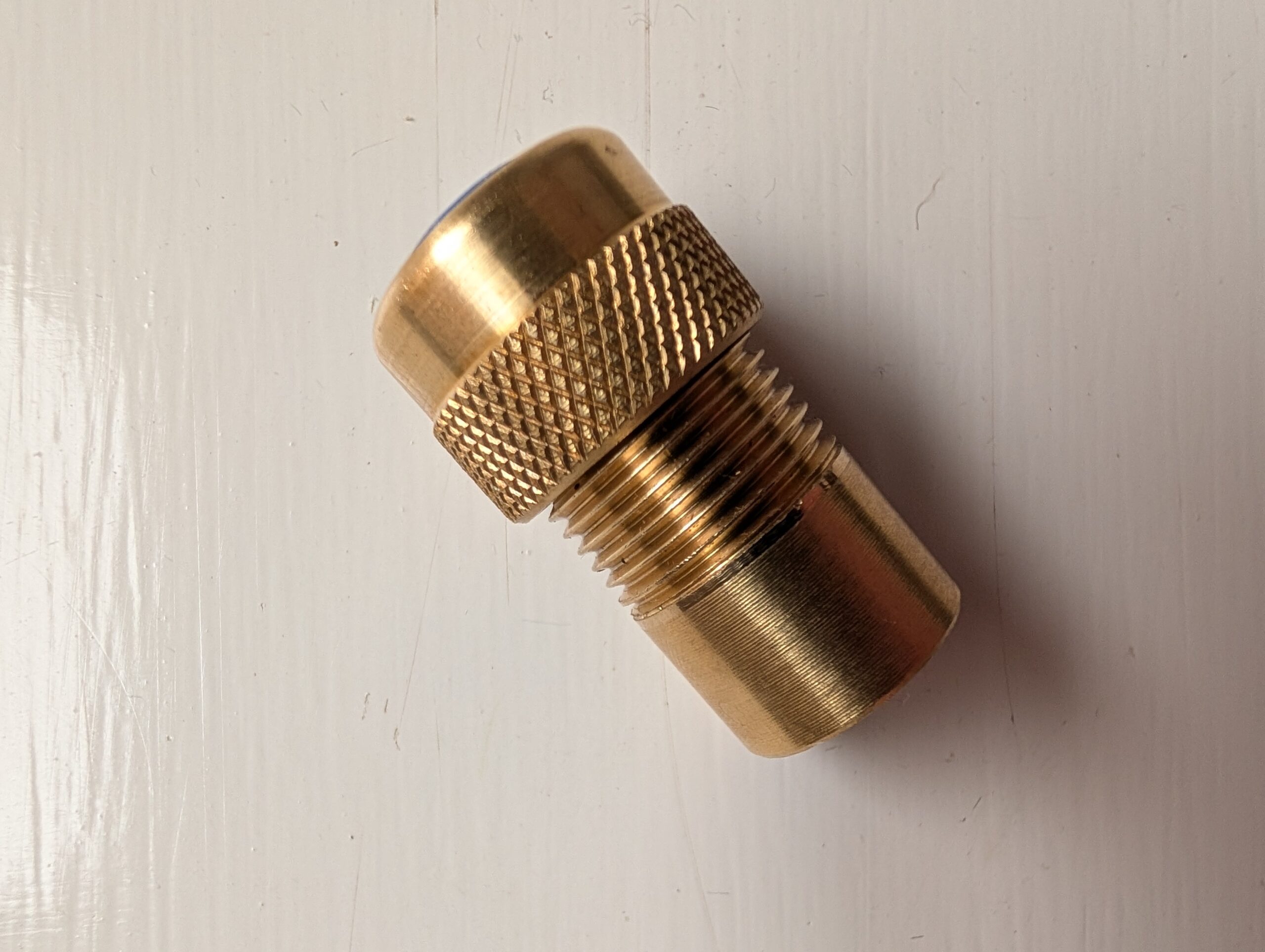 A brass threaded cylindrical connector with knurled grip.